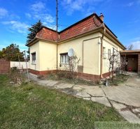 A family house in Kolárovo with a garden, paving, and a satellite dish on a yellow facade.