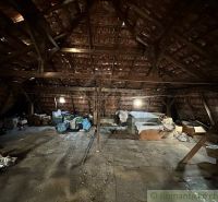 Attic in a family house with a sloped roof, stored items and diffuse light.