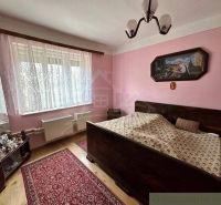 A bedroom with a double bed, wood-patterned flooring, and pink walls in a family house.