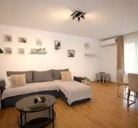 A comfortable living space in a holiday apartment with wood-patterned flooring and a dining table.