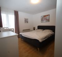 Bedroom with a bed and a baby crib in a holiday apartment, floor with wood decor.