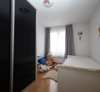 Children's room in a recreational apartment with a bed, wardrobe, and plush toys on the floor with wooden decor.