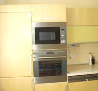 A kitchen in a 2-room apartment with built-in appliances and light furniture.