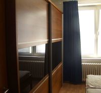 Sliding door wardrobe, bed, and radiator in the bedroom of a two-room apartment.