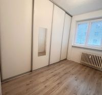 A room in a 3-room apartment with a white wardrobe and a wooden decor floor.