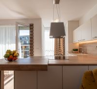 A kitchen in a 2-room apartment with an open balcony and wooden floor decor.