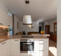 A kitchen in a 2-room apartment with a wooden decor floor and white cabinets.