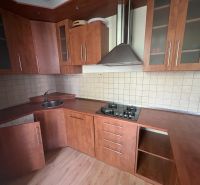 A kitchen in a 2-room apartment with a wooden decor floor and a brown kitchen unit.