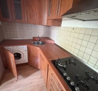 A kitchen in a 2-room apartment with a wooden decor floor and built-in appliances.