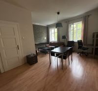 Interior of a 2-room apartment with a wooden decor floor, table, and chair.