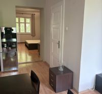 Interior of a 2-room apartment with a wooden decor floor, seating area, and entrance to the bedroom.
