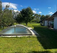A family house in Čalovecká garden with a pool under an arched cover and a grassy area.