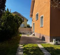 A family house in Čalovec with an orange facade, a lawn, and a paved driveway.