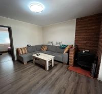 Living room in a family house with a wooden decor floor and a tiled stove.