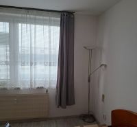 A room with a bed, windows, and a floor with wooden decor in a two-room apartment.
