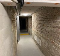 A corridor in the basement with brick walls and gray doors.