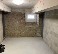 Basement room with concrete walls and a window in a two-room apartment.