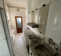 A kitchen in a 2-room apartment with white cabinets and tiled flooring.