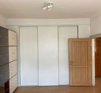 Interior of a 2-room apartment with a white wardrobe and shelving unit, floor with wood decor.