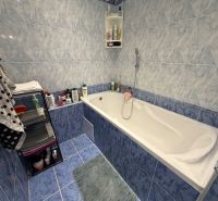 A bathroom with a bathtub and blue tiles in a 2-room apartment.