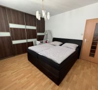 Bedroom in a 2-room apartment with a large wardrobe and a floor with a wooden decor.