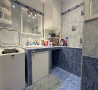 A bathroom in a 2-room apartment with a washing machine and blue tiles.