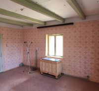 A room in a family house with retro wallpaper, a heating unit, and a floor with a wooden decor.