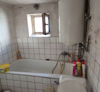 A bathroom in a family house with tiles, a bathtub, and a boiler.