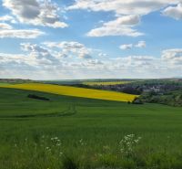 The village offers a breathtaking view of the green landscape with a blue sky and clouds.