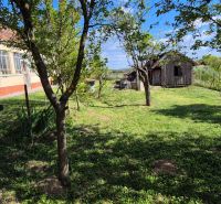 A family house in Dedinka with a glassed-in veranda, a garden, and a wooden structure in the yard.