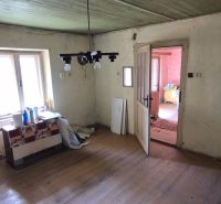 A room in a family house with a wooden decor floor, older furniture, and a window.