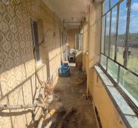 The family house has an enclosed porch with older windows and a patterned wall.