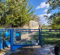 A family house in Dedinka with a blue gate and a garden full of greenery.