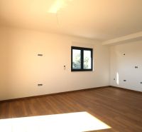 A spacious room with a large window and a wooden decor floor in a Holiday Apartment.