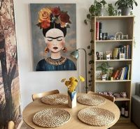 Dining room in a 2-room apartment with a painting, wooden table, and decorative accessories.