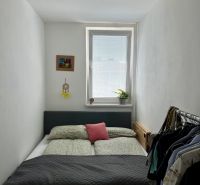 A cozy bedroom with a bed, a painting, and a wardrobe in a 2-room apartment.