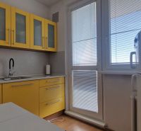 A kitchen with yellow cabinets in a 2-room apartment, floor with wood decor.
