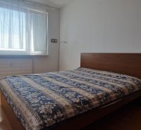 Bedroom with a bed and wooden decor flooring in a 2-room apartment.