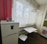 A kitchen in a 3-room apartment, with a refrigerator and a table, curtains, red checkered drapes.
