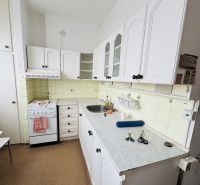 A kitchen with white cabinets and a stove in a 3-room apartment.