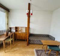 A room in a 3-bedroom apartment with a wood-patterned floor, furniture, and decorative accessories.