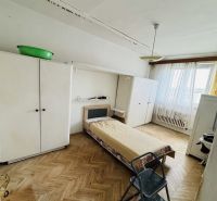 A room with a bed, a wardrobe, and a floor with a wooden decor in a 3-room apartment.
