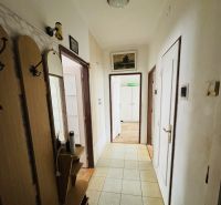A hallway of a 3-room apartment with entrances to other rooms and tiled flooring.
