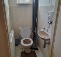 A bathroom in a 4-room apartment with a sink, toilet, and window.