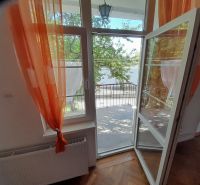 Open balcony with a view and orange curtains, floor with wooden decor.