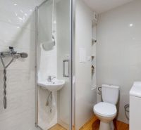 Bathroom with toilet, shower, sink, and washing machine in a studio apartment.