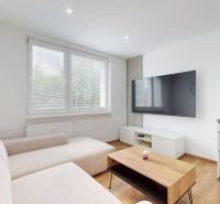 Living room with a television, sofa, and a table on a wooden floor.