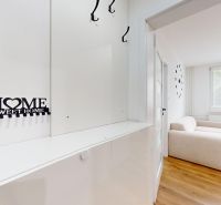 Entrance hallway with a mirror and a light sofa in a studio apartment with a wood-patterned floor.