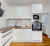 The kitchen in a studio apartment with white cabinets and a wood-patterned floor.
