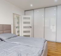 A bedroom in a one-room apartment with a bed, a wardrobe, and a wooden decor floor.